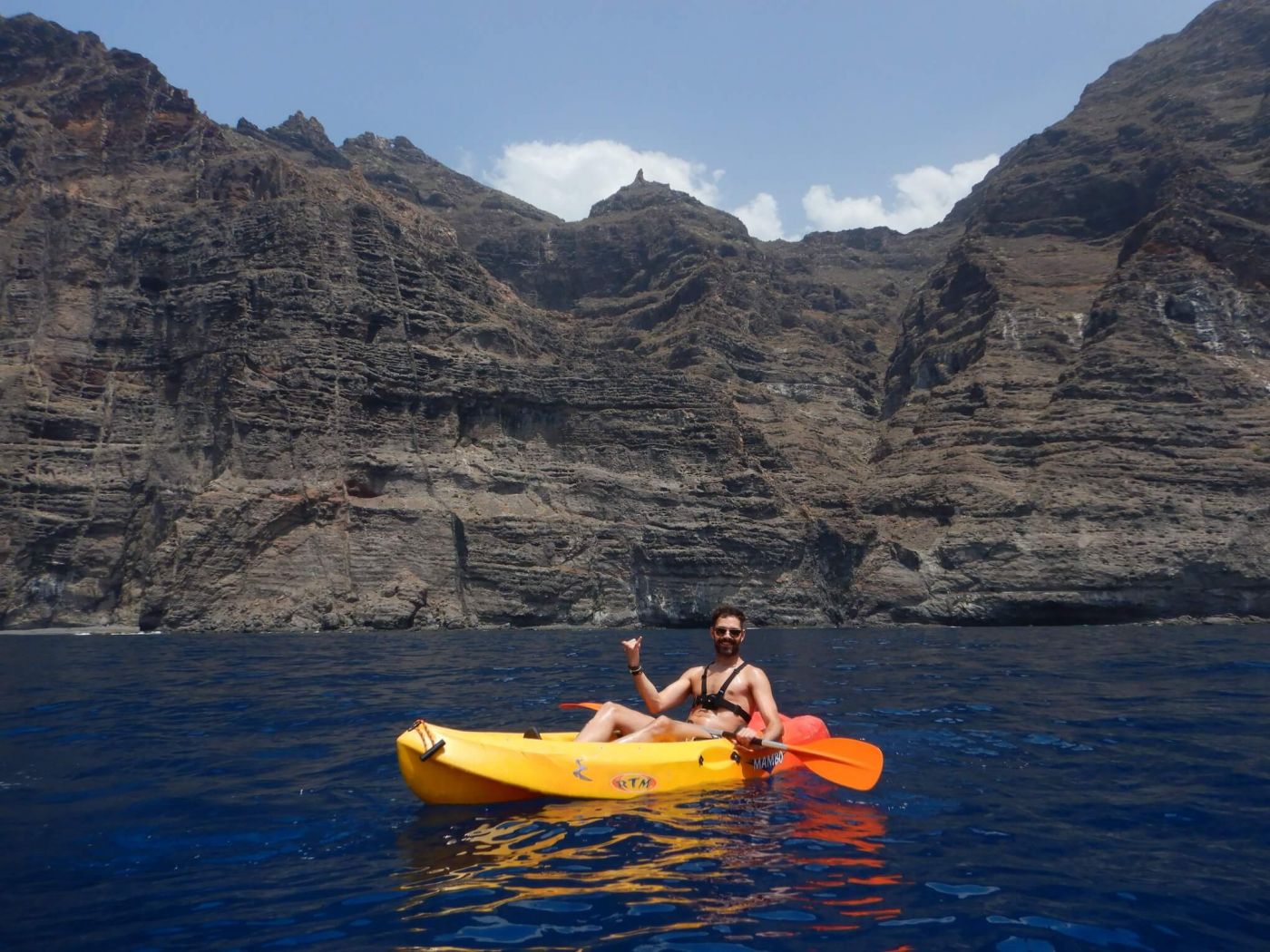 Person kayaking in Tenerife with the cliffs of the giants in the background