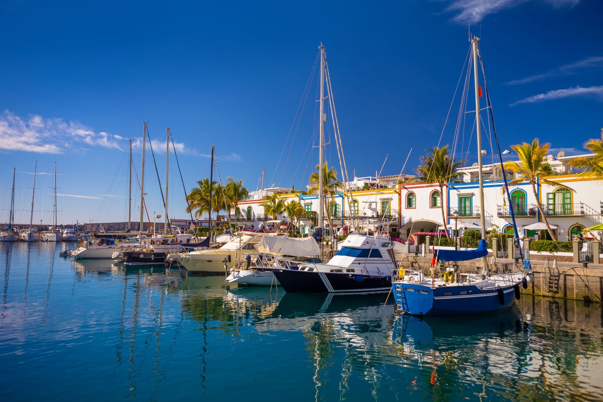 Boats moored in Puerto de Mogán harbour with white houses behind