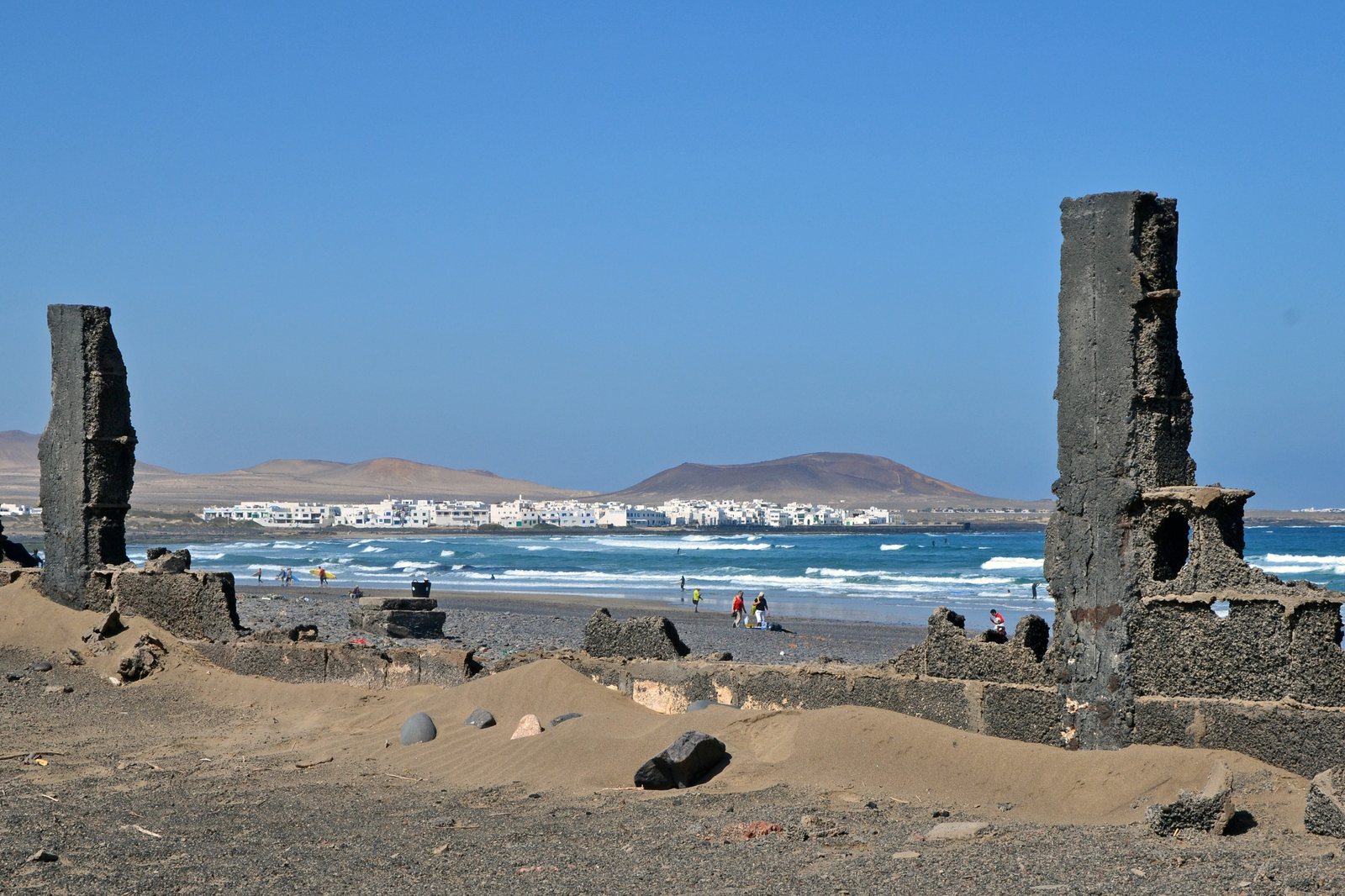 Surfista cabalgando una ola frente al Risco de Famara en Lanzarote