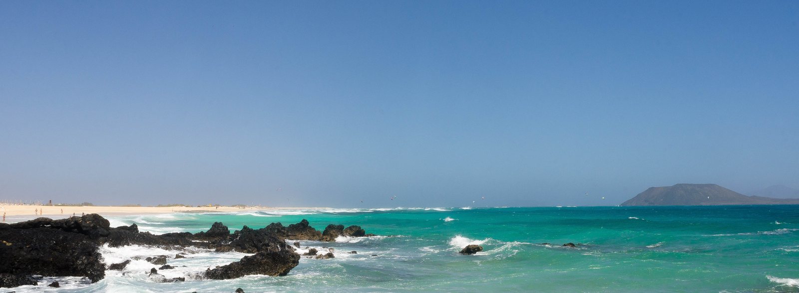Aguas cristalinas y arena blanca en las Grandes Playas de Corralejo con Isla de Lobos de fondo